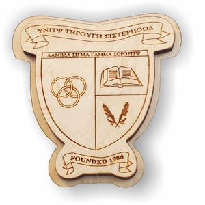 May include: A wooden plaque with a shield-shaped design, featuring a book, three interlocking rings, and a pair of feathers. The plaque has a banner at the top with the text "Unity Through Sisterhood" and another banner at the bottom with the text "Founded 1986".