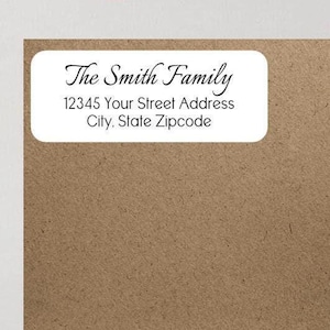 May include: A white rectangular address label with rounded corners, featuring the text "The Smith Family" and an address. The label is set against a brown background. The image also includes a pink circular logo with the text "ink paper parties".