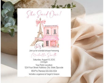 May include: A white bridal shower invitation card featuring a watercolor illustration of the Eiffel Tower with a pink bow, a pink building, and a bicycle. The text reads She Said Oui! Join us for a bridal shower honoring Michelle Smith.