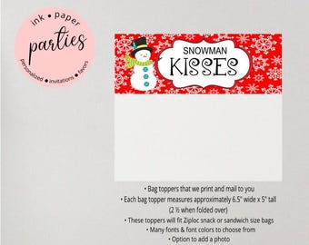 May include: A red bag topper with a snowman design and the words "Snowman Kisses". The bag topper measures approximately 6.5 inches wide by 5 inches tall. The design includes a snowman wearing a hat and scarf.
