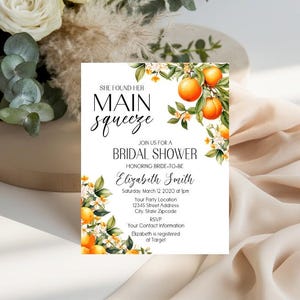 May include: A rectangular bridal shower invitation card featuring watercolor illustrations of oranges and white blossoms. The text reads: She found her main squeeze, join us for a bridal shower honoring bride-to-be Elizabeth Smith, Saturday, March 12 2020 at 1pm.