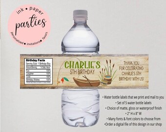 May include: A clear plastic water bottle featuring a personalized label with a wood grain background, a fishing boat illustration, and text reading Charlie's 5th Birthday. The label includes a nutrition facts style box and measures 2 inches by 8 inches.