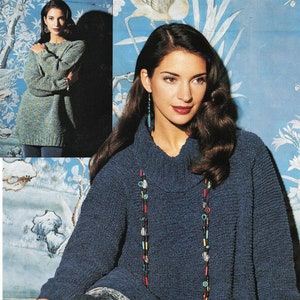 May include: A woman wearing a blue knitted sweater with a turtleneck and a long beaded necklace. She is sitting on a blue couch with her legs crossed.