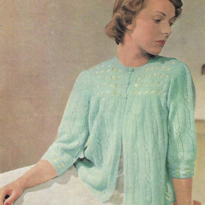 May include: A light blue knitted cardigan with a diamond pattern and a button fastening. The cardigan has a delicate lace trim around the neckline and sleeves.