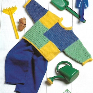 May include: A knitted baby sweater with a patchwork design in blue, green, and yellow. The sweater is laid out on a white wooden surface with a rake, two small pots, a green shovel, and a green watering can.