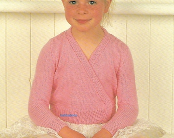 May include: A pink knitted wrap cardigan with a V-neck and long sleeves. The cardigan is worn over a white tulle skirt.