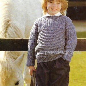May include: A purple knitted jumper with a ribbed pattern. The jumper has a crew neck and long sleeves. The jumper is being worn by a child standing next to a white horse.