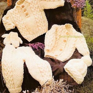 May include: A set of knitted baby clothes in a cream color. The set includes a cardigan, a sweater, and a pair of pants. The clothes are made with a cable knit pattern.