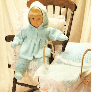 May include: A knitted baby doll outfit in a light blue colour, including a hooded jacket, trousers, and a matching blanket. The outfit is displayed on a doll sitting in a rocking chair.