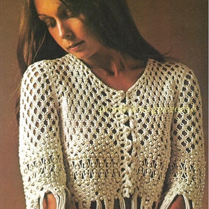 May include: A white crocheted top with a button closure and beaded trim. The top has fringe detailing on the sleeves and bottom hem.