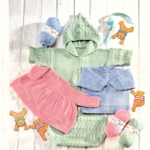 May include: Three knitted baby outfits, one pink, one blue, and one green, with matching yarn balls. The green outfit has a hood. The outfits are laid out on a white wooden surface.