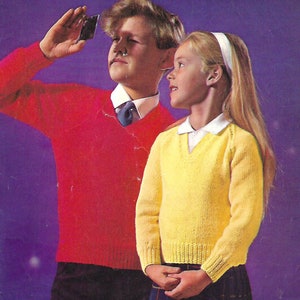 May include: Two children wearing knitted sweaters. The boy is wearing a red sweater and the girl is wearing a yellow sweater. They are both looking at something off camera.
