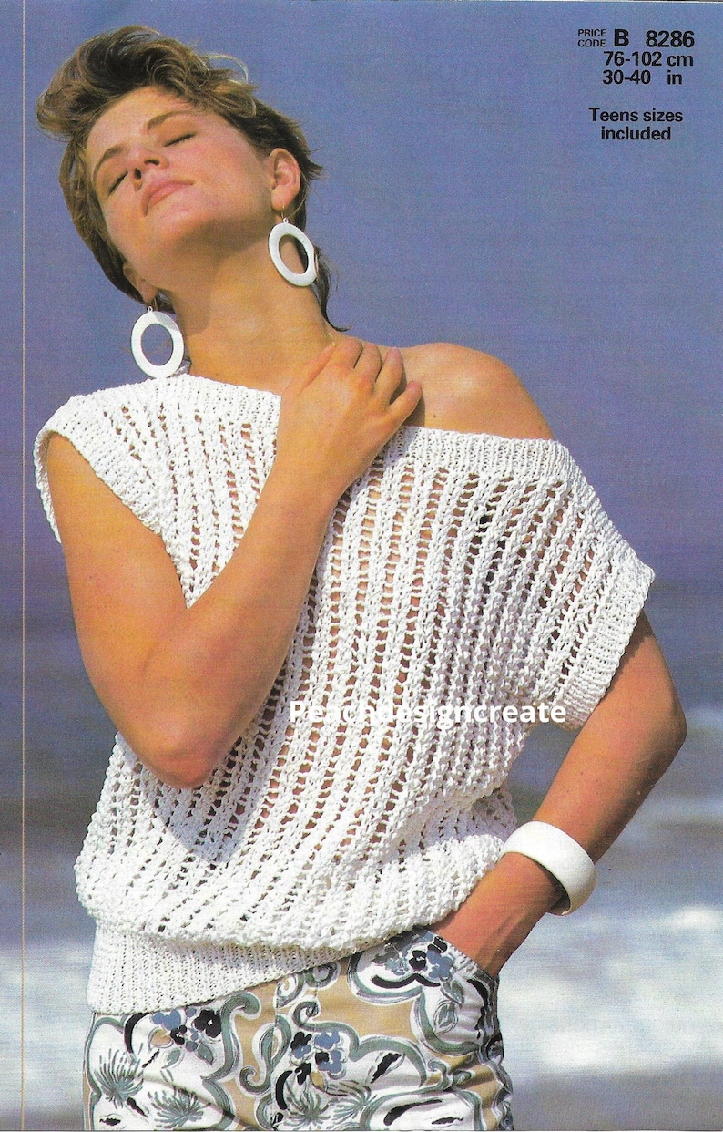 May include: White crochet top with a loose, open-weave design. The top has short sleeves and a slightly off-the-shoulder neckline. The model is wearing the top with a pair of floral print trousers. The text on the image reads "PRICE CODE B 8286 76-102 cm 30-40 in Teens sizes included".
