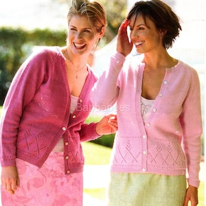 May include: Two women in pink knit cardigans. The cardigans feature a button-down front and a diamond pattern near the hem. One woman wears a pink skirt, the other a light green skirt. The image has soft lighting, suggesting an outdoor setting.