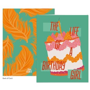 May include: A birthday greeting card with a teal background and a cake illustration. The cake has pink, orange, and white layers with a lit candle. The text reads "THE LIFE OF A BIRTHDAY GIRL." The back of the card has an orange feather pattern.