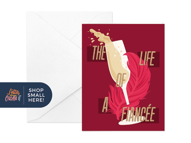May include: A burgundy greeting card with a champagne glass design and the text "THE LIFE OF A FIANC&Eacute;E" in gold. A white envelope is on the left. The image includes a pink feather and bubbly liquid.