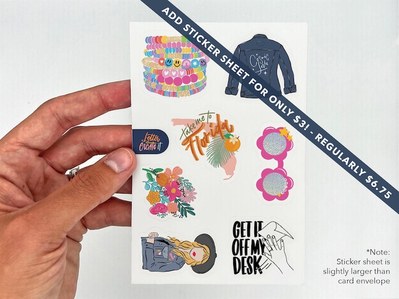 May include: A sticker sheet featuring various colorful designs, including a denim jacket, floral arrangements, sunglasses, and the phrase "Take me to Florida." The sheet is held by a hand.