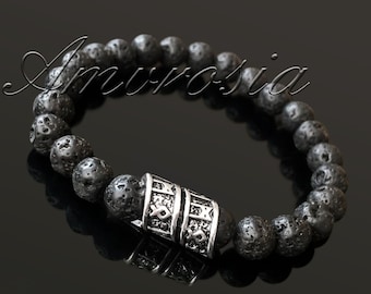 May include: Black lava rock beaded bracelet with a silver charm featuring a repeating pattern of runes. The bracelet is on a black background.
