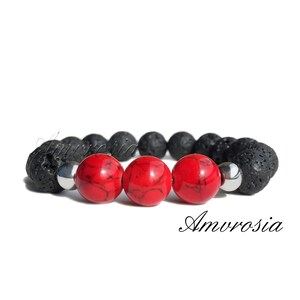 May include: A black lava rock and red gemstone bracelet with silver metal beads. The bracelet has three red gemstone beads and is made with natural materials.