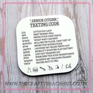 May include: A white coaster with black text listing senior citizen texting code abbreviations and their meanings. The coaster also includes icons of a walker, dentures, glasses, a wheelchair, a scooter, and a house with a heart.