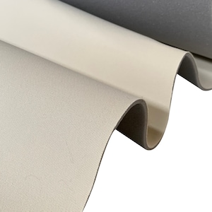 May include: Close-up of a white fabric with a textured surface. The fabric is folded over a grey fabric.