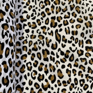 May include: White fabric with a brown and black leopard print pattern.