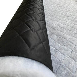 May include: A roll of black quilted fabric with a white backing. The fabric has a diamond pattern and is used for upholstery or crafts.