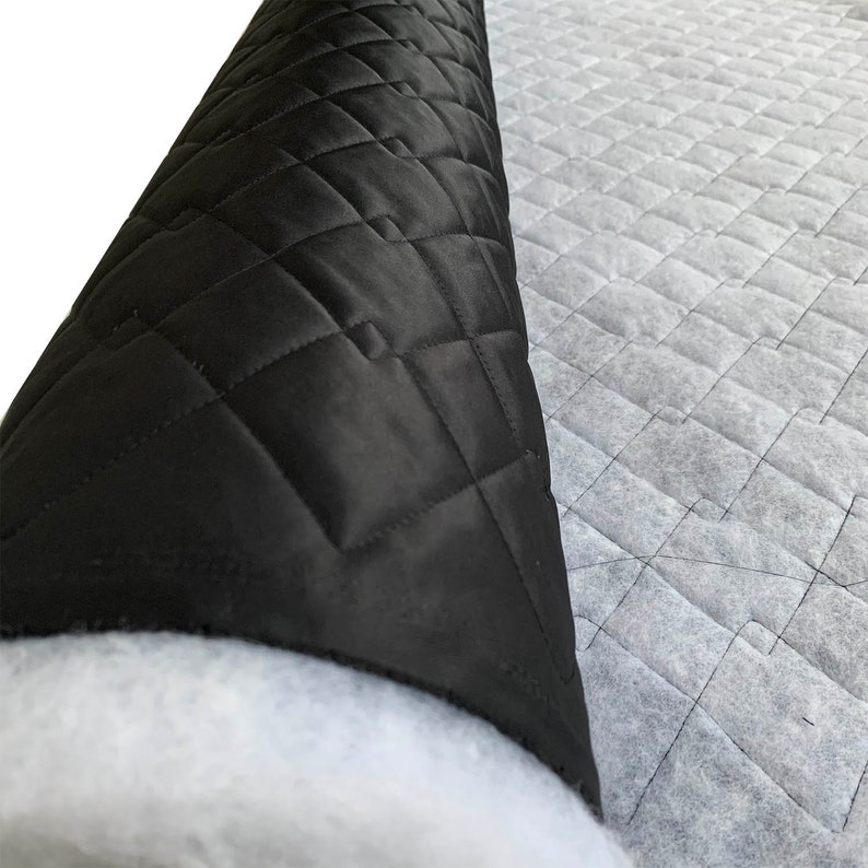 May include: A roll of black quilted fabric with a white backing. The fabric has a diamond pattern and is used for upholstery or crafts.