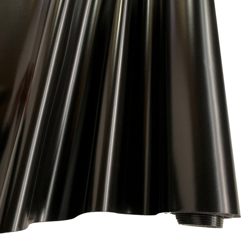 May include: A roll of black vinyl fabric with a shiny, smooth finish. The fabric is rolled up and the end is visible.