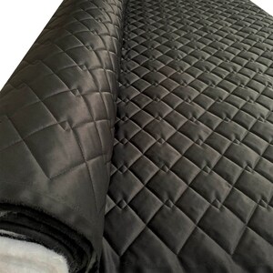 May include: Black quilted fabric with a diamond pattern. The fabric is rolled up and the quilted pattern is visible.