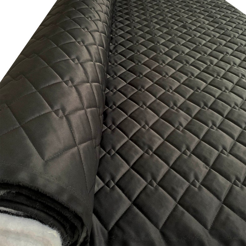 May include: Black quilted fabric with a diamond pattern. The fabric is rolled up and the quilted pattern is visible.