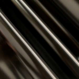 May include: Close-up of black fabric with a subtle textured pattern. The fabric has a smooth, glossy finish.