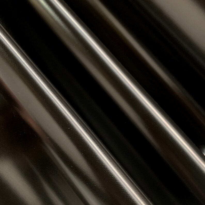 May include: Close-up of black fabric with a subtle textured pattern. The fabric has a smooth, glossy finish.