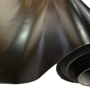May include: A roll of black fabric with a shiny, satin-like finish. The fabric is rolled up tightly and has a black seam along the edge.