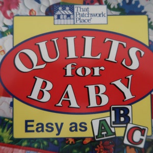 May include: A book cover with the title "QUILTS for BABY" in white letters on a red oval. The cover also features the text "Easy as ABC" and a logo for "That Patchwork Place". The background shows a colorful quilt.