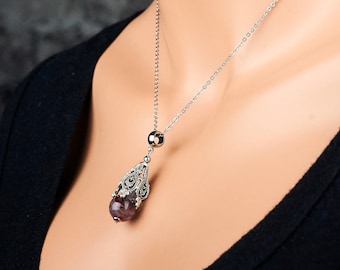 May include: A silver chain necklace with a pendant featuring a purple gemstone encased in a filigree design.