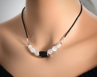 May include: A black leather necklace with white moonstone beads and a black tourmaline pendant.