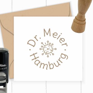 May include: A brown rubber stamp with a circular design featuring the text "Dr. Meier Hamburg" and a stylised image of a virus. The stamp is on a white card.