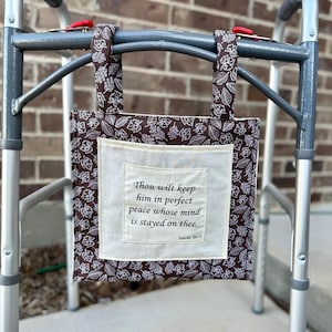Może przedstawiać: Brązowo-biała torba na chodzik z kremową kwadratową kieszenią. Torba jest przymocowana do srebrnego chodzika. Kieszeń zawiera tekst "Thou wilt keep him in perfect peace whose mind is stayed on thee. Isaiah 26:3."