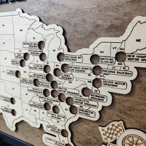 Pu&ograve; includere: Una mappa in legno degli Stati Uniti con dei buchi che rappresentano diversi circuiti NASCAR. La mappa &egrave; etichettata con i nomi di ogni circuito, tra cui il Daytona International Speedway, il Talladega Superspeedway e il Charlotte Motor Speedway.