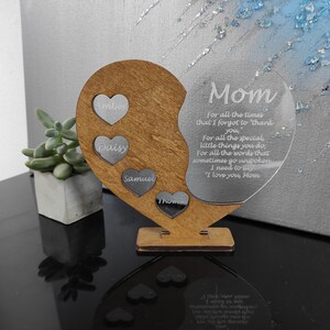 May include: A wooden heart-shaped plaque with a clear acrylic heart insert. The acrylic heart has a message for Mom and the wooden heart has four smaller hearts with the names Amber, Daisy, Samuel, and Thomas engraved on them.