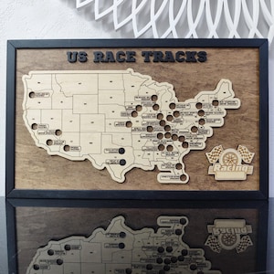Pu&ograve; includere: Una mappa in legno degli Stati Uniti con punti neri che segnano le posizioni degli autodromi americani. La mappa &egrave; incorniciata in legno nero e ha il testo "US RACE TRACKS" in alto. L'angolo in basso a destra della mappa ha una bandiera da corsa in legno e la parola "Racing".