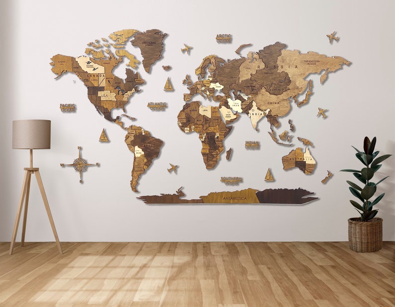 Puede incluir: Un mapa del mundo de madera con un acabado marr&oacute;n claro. El mapa est&aacute; montado en una pared blanca e incluye una br&uacute;jula y peque&ntilde;os aviones. El mapa est&aacute; hecho de piezas individuales de madera que se ensamblan para formar los continentes.