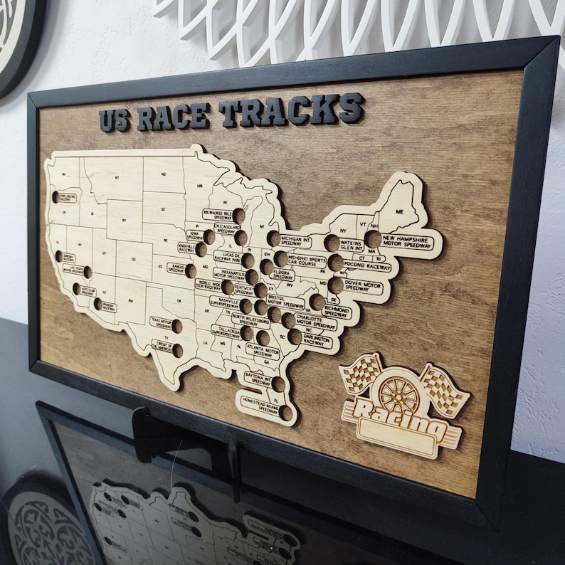 Pu&ograve; includere: Una mappa in legno degli Stati Uniti con cerchi neri che segnano le posizioni degli autodromi degli Stati Uniti. La mappa &egrave; incorniciata in nero e ha il testo "US RACE TRACKS" nella parte superiore. La parte inferiore della mappa ha una bandiera a scacchi e la parola "Racing" in uno stendardo.