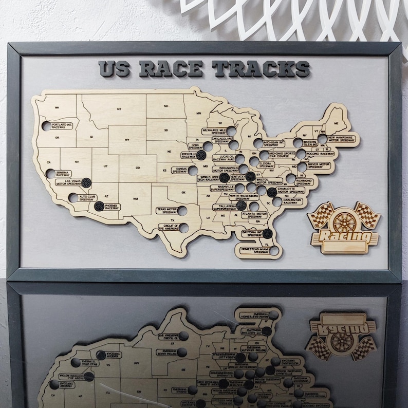 Pu&ograve; includere: Una mappa in legno degli Stati Uniti con punti neri che segnano le posizioni degli autodromi americani. La mappa &egrave; incorniciata da una cornice grigia e ha il testo "US Race Tracks" in alto. L'angolo in basso a destra della mappa ha un cartello in legno che dice "Racing" con una bandiera a scacchi e una gomma.