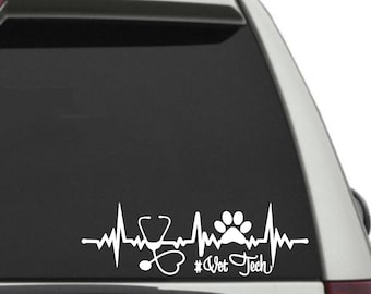 May include: White vinyl decal featuring a heartbeat line with a stethoscope, paw print, and the text "#Vet Tech". The design is suitable for application on a car window or other smooth surfaces.