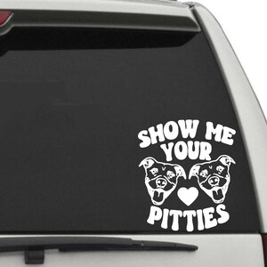 May include: White vinyl decal featuring the phrase "SHOW ME YOUR PITTIES" with two dog faces and a heart. The decal is designed to be applied to a car window or similar surface.