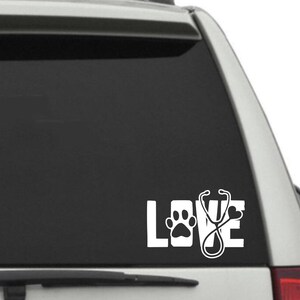 Op de afbeelding: Witte vinyl sticker met het woord "LOVE" in grote letters, een pootprint in de "O" en een stethoscoop in de "V".