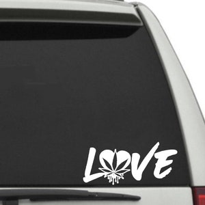 Op de afbeelding: Een witte vinyl sticker met het woord "LOVE" in een gestileerd lettertype. De "O" is vervangen door een marihuanablad in de vorm van een hart.