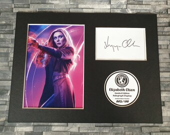 May include: A black framed photograph of Elizabeth Olsen as Scarlet Witch from the Marvel Cinematic Universe. The photograph is signed by Elizabeth Olsen and includes a limited edition autograph display numbered 003/100.